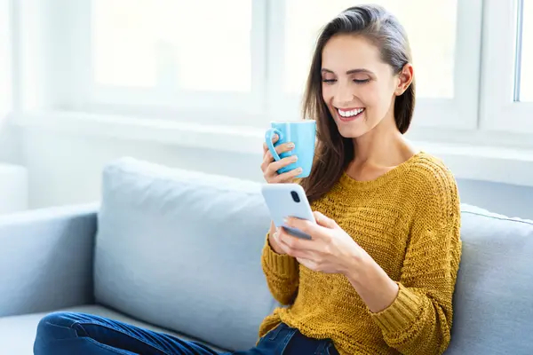 Woman holding a coffee while scrolling through an employee program on her phone