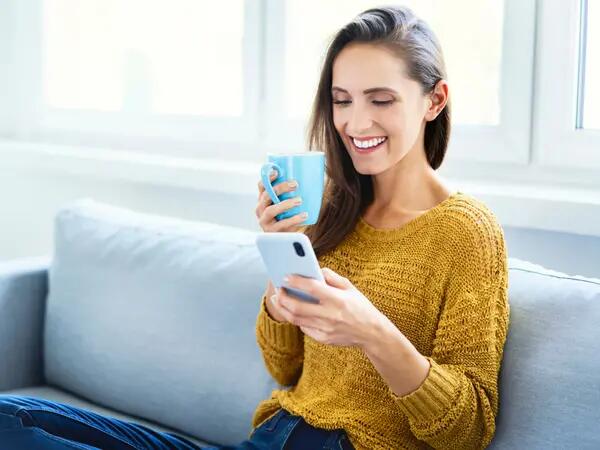 Woman holding a coffee while scrolling through an employee program on her phone.
