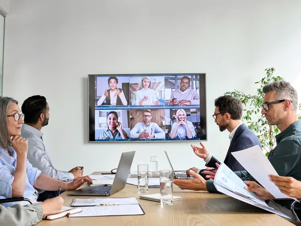 Diverse employees on online conference video call on tv screen in meeting room
