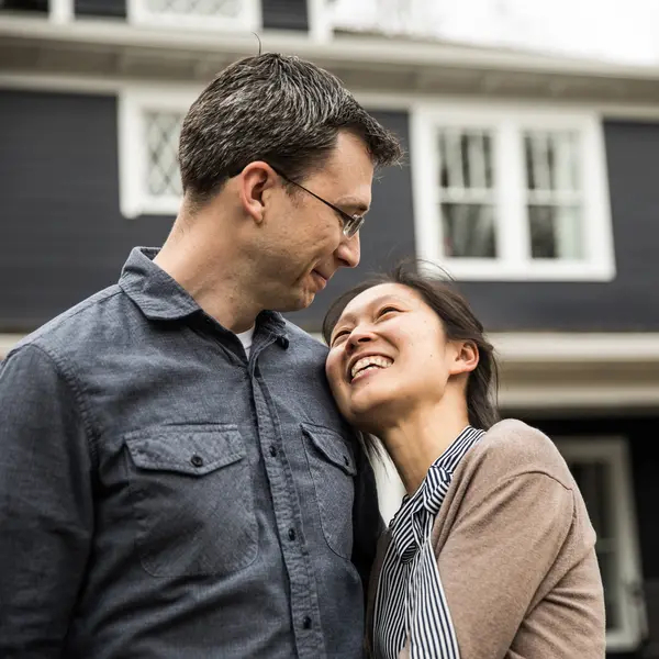 Couple smiling at each other outside their home