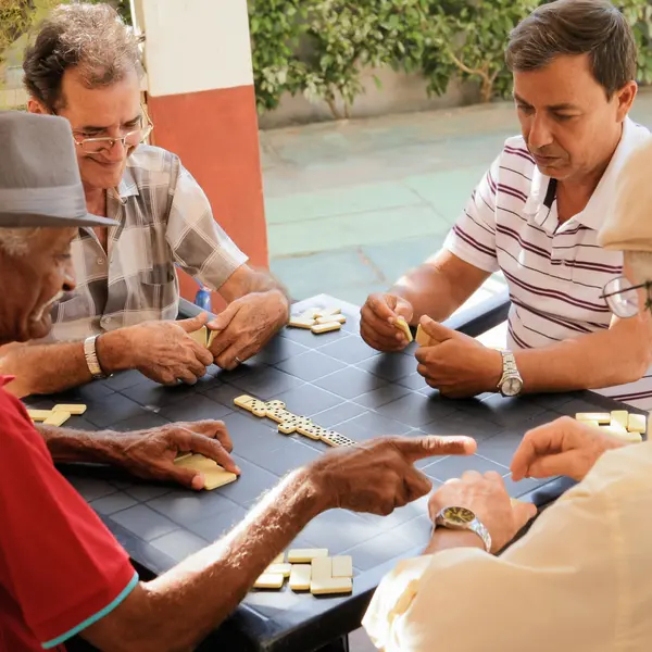 Old men playing dominos around table